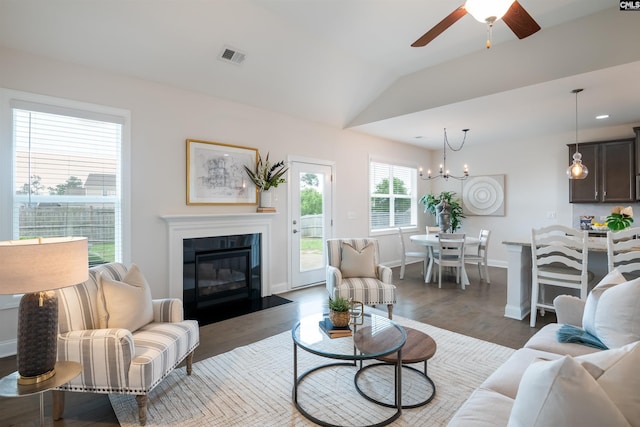 living room with a chandelier, a tile fireplace, a ceiling fan, vaulted ceiling, and wood finished floors
