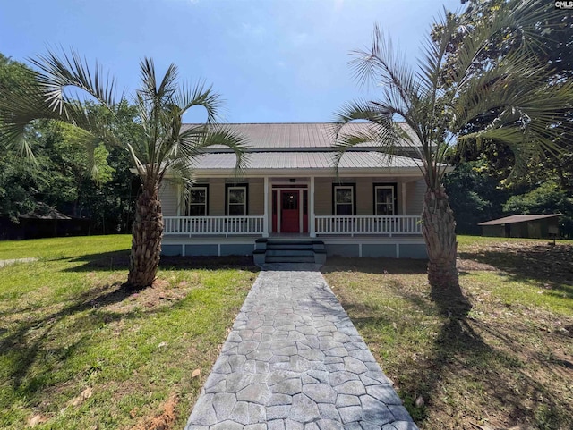view of front facade featuring covered porch, a front yard, and metal roof
