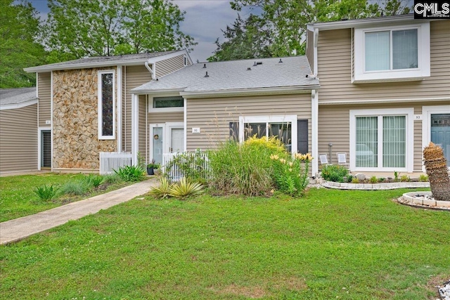 rear view of house featuring a lawn and stone siding