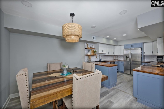 dining room featuring light wood finished floors, recessed lighting, and baseboards