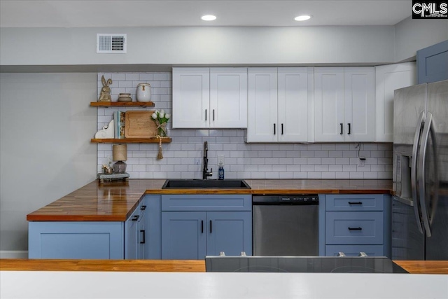 kitchen featuring appliances with stainless steel finishes, wooden counters, a sink, blue cabinetry, and recessed lighting