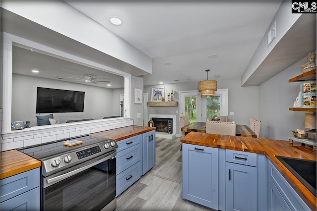 kitchen with butcher block countertops, stainless steel electric stove, blue cabinetry, light wood finished floors, and open floor plan