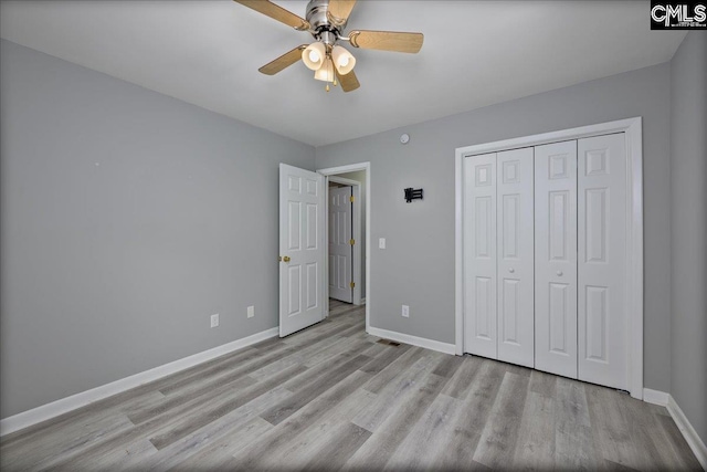 unfurnished bedroom featuring baseboards, wood finished floors, and a closet