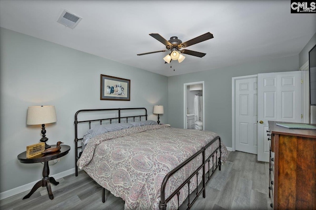 bedroom featuring light wood-style floors, baseboards, and ensuite bath