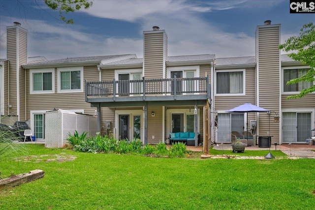 back of property featuring outdoor lounge area, a yard, a chimney, and a deck