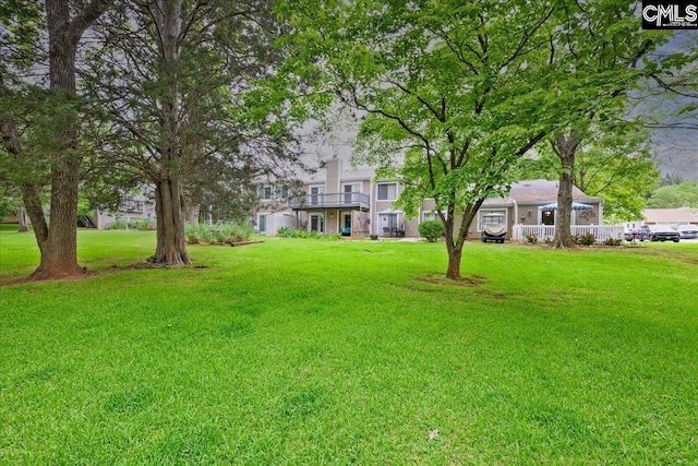 view of green lawn featuring a balcony