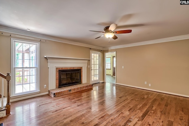 unfurnished living room featuring a ceiling fan, crown molding, wood finished floors, a fireplace, and baseboards