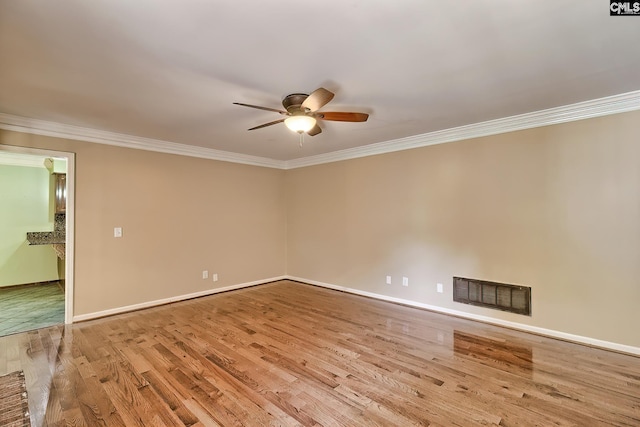 spare room with a ceiling fan, crown molding, wood finished floors, and baseboards