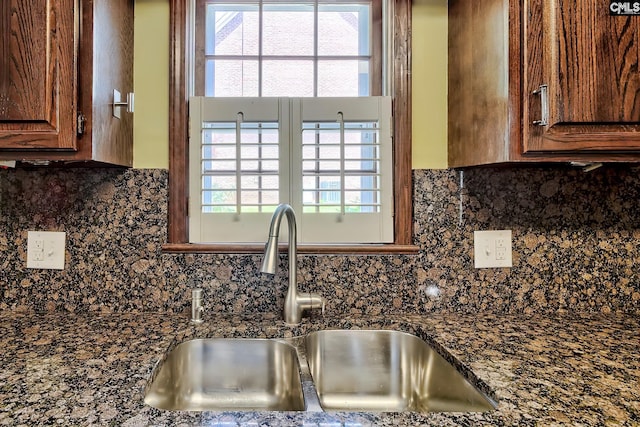 kitchen with a sink, dark countertops, and tasteful backsplash