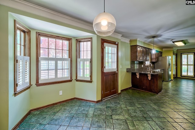 kitchen with baseboards, tasteful backsplash, ornamental molding, a sink, and pendant lighting