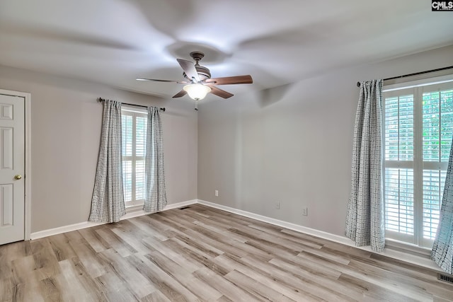unfurnished room with healthy amount of natural light, a ceiling fan, and wood finished floors