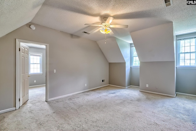 bonus room with a textured ceiling, carpet floors, healthy amount of natural light, ceiling fan, and lofted ceiling