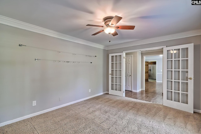 carpeted empty room featuring french doors, crown molding, ceiling fan, and baseboards
