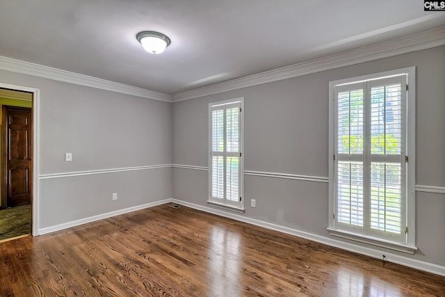 empty room featuring wood finished floors, ornamental molding, and baseboards
