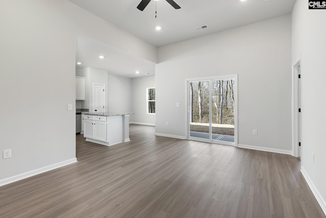 unfurnished living room with ceiling fan, wood finished floors, baseboards, and recessed lighting