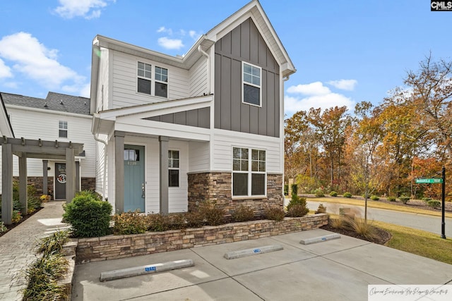 view of front facade featuring board and batten siding, stone siding, and a pergola