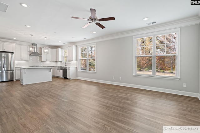 unfurnished living room featuring ornamental molding, ceiling fan, recessed lighting, baseboards, and wood finished floors