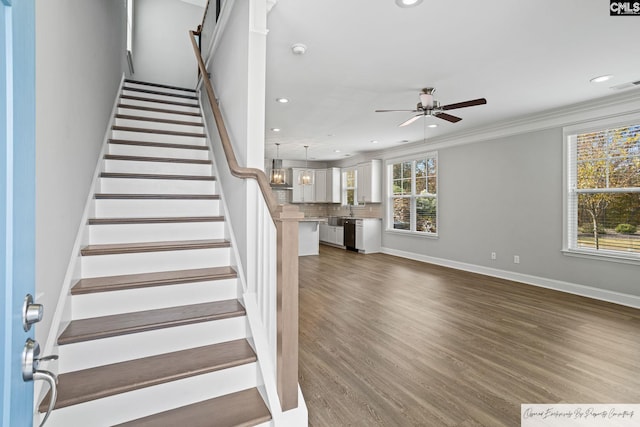 stairs with a ceiling fan, recessed lighting, wood finished floors, baseboards, and ornamental molding