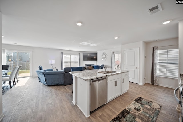 2109 Elmridge Rd, Columbia, SC 29209 - kitchen with stainless steel dishwasher, a sink, white cabinetry, light wood-style flooring, and a center island with sink