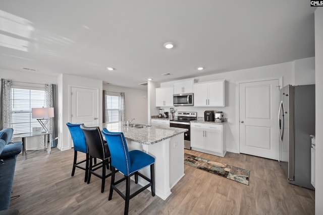 2109 Elmridge Rd, Columbia, SC 29209 - kitchen featuring stainless steel appliances, a sink, a kitchen bar, light wood finished floors, and white cabinets