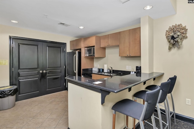 1320 Pulaski St Unit B207, Columbia, SC 29201 - kitchen with stainless steel appliances, a peninsula, a breakfast bar area, light tile patterned floors, and a sink