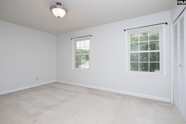 unfurnished room featuring light carpet and baseboards