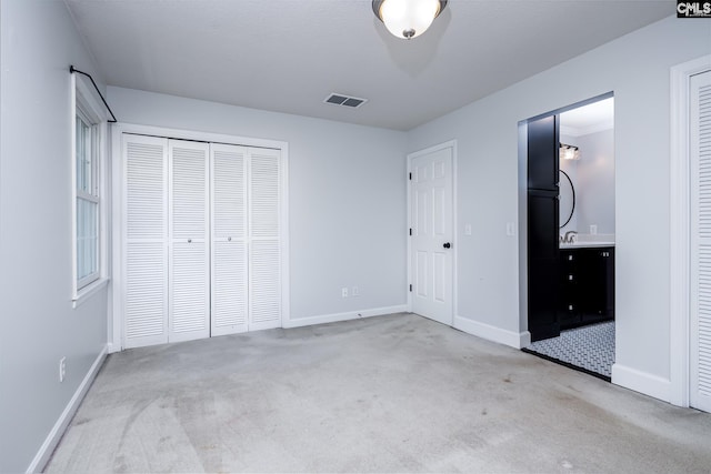 unfurnished bedroom with carpet floors, baseboards, a closet, and ensuite bathroom