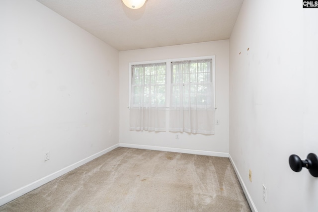 unfurnished room with carpet, baseboards, and a textured ceiling