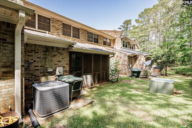 view of grassy yard featuring central AC and a sunroom
