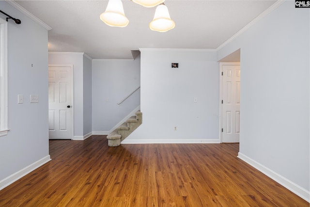 empty room with crown molding, stairs, wood finished floors, and baseboards