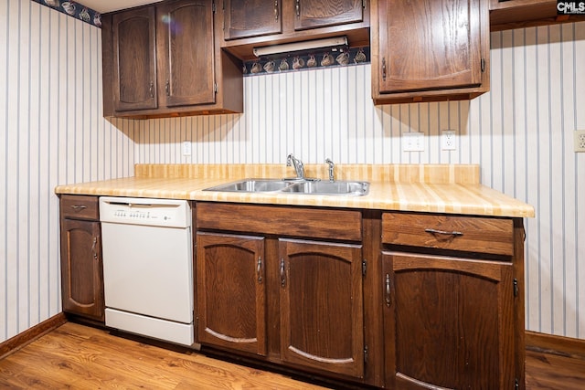 kitchen with dishwasher, a sink, wallpapered walls, wood finished floors, and light countertops