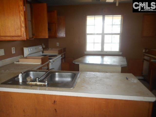 2133 Slighs Ave, Columbia, SC 29204 - kitchen featuring white range with electric stovetop, a sink, light countertops, brown cabinets, and a center island