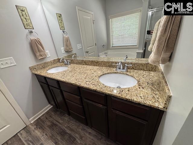 404 Coopers Edge Ln, Blythewood, SC 29016 - bathroom featuring wood finished floors, double vanity, a garden tub, and baseboards