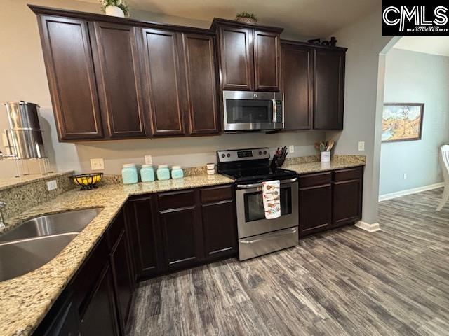 404 Coopers Edge Ln, Blythewood, SC 29016 - kitchen with appliances with stainless steel finishes, a sink, dark wood-style flooring, dark brown cabinetry, and light stone countertops