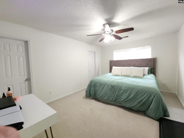 carpeted bedroom featuring baseboards, ceiling fan, and a textured ceiling
