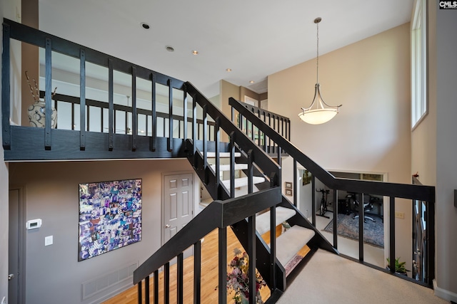 stairs featuring a high ceiling and wood finished floors