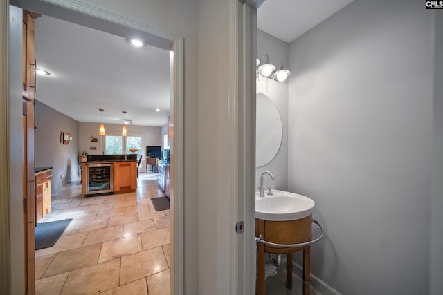 bathroom featuring a sink, beverage cooler, stone tile floors, baseboards, and recessed lighting