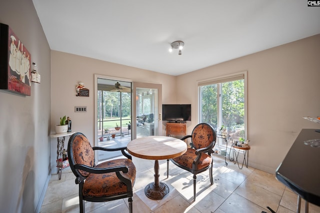 dining space featuring baseboards, ceiling fan, and light tile patterned floors
