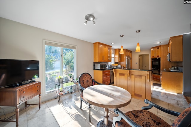 kitchen featuring dark countertops, high quality fridge, a kitchen island, pendant lighting, and brown cabinets