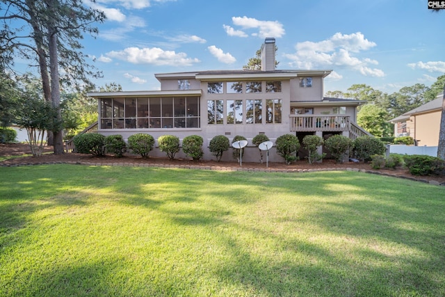 back of property featuring a sunroom, a chimney, a lawn, stucco siding, and stairs