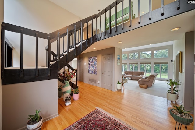 stairs featuring wood finished floors, a high ceiling, and baseboards