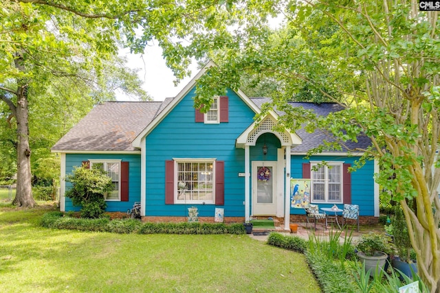 view of front of home featuring roof with shingles and a front yard