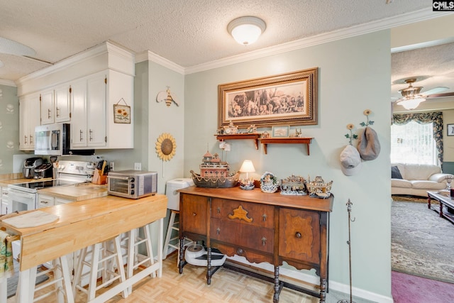 kitchen with stainless steel microwave, crown molding, a textured ceiling, white cabinets, and light countertops