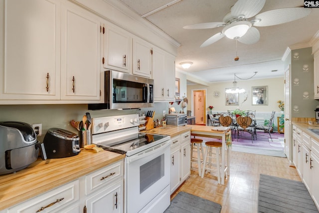 kitchen featuring white electric range oven, stainless steel microwave, ornamental molding, white cabinetry, and ceiling fan