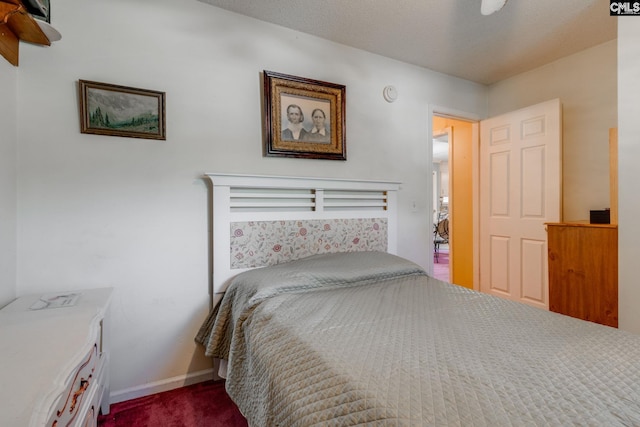bedroom featuring dark carpet and baseboards