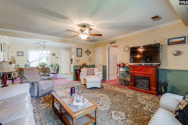 living room with crown molding, a chandelier, ceiling fan, a glass covered fireplace, and a textured ceiling