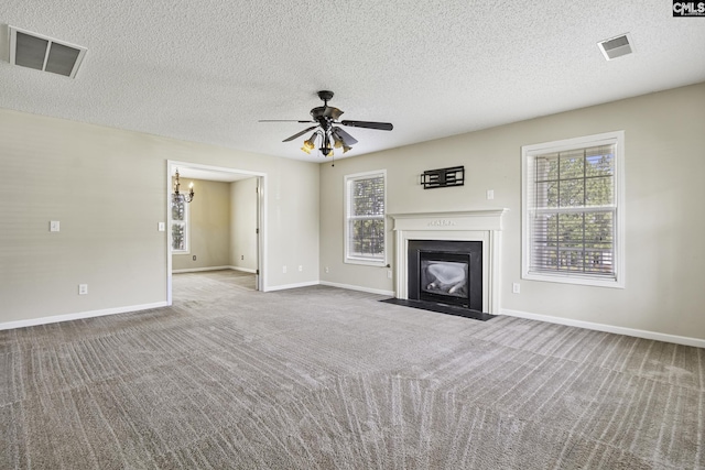 unfurnished living room with a fireplace with flush hearth, carpet flooring, ceiling fan, a textured ceiling, and baseboards