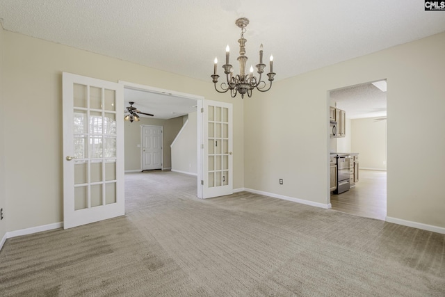 spare room featuring french doors, light carpet, a chandelier, baseboards, and ceiling fan