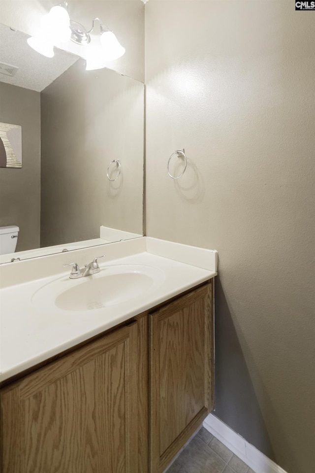 half bathroom with vanity, tile patterned floors, toilet, and baseboards