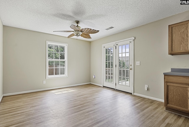 unfurnished room featuring light wood-type flooring, ceiling fan, baseboards, and a textured ceiling